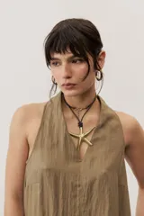 Vestido largo color marrón, sin mangas y con escote halter. Cuenta con bolsillos laterales y corte holgado.