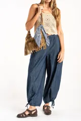 Pantalón tipo jean de corte wide leg y diseño balloon, con cintura elástica y cordones ajustables en los tobillos. Confeccionado en algodón denim de tono azul oscuro.