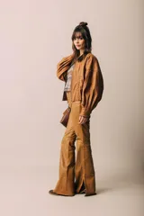 Campera de cuero color camel, de silueta oversize y levemente corta. Cuenta con cierre frontal metálico, cuello redondo a la base y mangas amplias. Presenta detalles de costuras trenzadas en el frente.