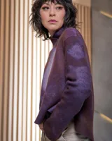 Sweater de lana merino afieltrada color uva con teñido artesanal tie dye en forma de luna. Tiene cuello alto cruzado y aberturas laterales traseras.