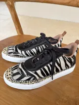 Championes de cuero con diseño de animal print combinado, presentando patrón de cebra en el cuerpo y detalles de leopardo en la puntera. Poseen cordones negros, suela blanca y forro interior en tono nude.