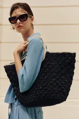 Bolso tipo cesta trenzada en color negro con asas de mano y bordes en tono tostado a contraste.