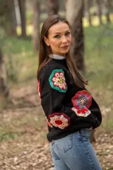 Sweater negro de lana con cuello redondo y apliques de flores de crochet multicolores.