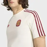 Remera Adidas de la colección España Originals, color blanco con detalles en bordó. Presenta el logo del trébol y el escudo de la selección española en el frente, con las icónicas tres tiras de la marca en los hombros y mangas.