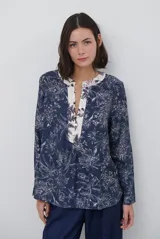 Blusa de manga larga con estampado floral en tonos azul marino y crema. Presenta un escote en V con tapeta abotonada en contraste y un corte holgado.
