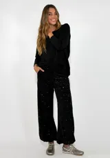 Pantalon de corte recto y holgado, confeccionado en tela cubierta de lentejuelas negras con forro interior.