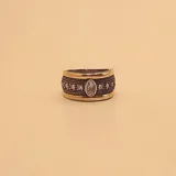 Anillo ancho de plata 925 y oro con acabado envejecido, presenta una banda central texturizada con una hilera de circonias pequeñas y una circonia central de mayor tamaño en forma ovalada.