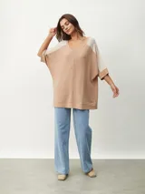 Remera oversize de manga corta con escote en V, de diseño bicolor en tonos beige y tostado, con mangas raglán y corte amplio.