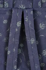Mochila de lona azul con estampado floral, asas de mano superiores unidas por una tira con broche, detalles en cuero sintético marrón, bolsillo frontal con cierre y compartimentos laterales.