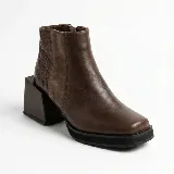 Bota corta de cuero vacuno color marrón, con diseño de paneles combinados en cuero liso y cuero texturizado. Presenta una puntera cuadrada, plataforma delantera y un taco geométrico ancho de altura media.