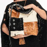 Bolso tipo hobo de cuero vacuno con diseño patchwork en tonos whisky, arena y negro. Tiene una manija corta y una correa larga ajustable. En cada uno de sus dos lados tiene un amplio bolsillo vertical con cierre. En su tapa trasera tiene un bolsillo con cierre. Su interior está forrado en tela de excelente calidad, y contiene un bolsillo con cierre y otro pequeño para el guardado del móvil.