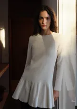 Vestido corto de punto fino con diseño evasé, cuello redondo y manga larga. Presenta un acabado acanalado con detalle de tablas en el ruedo.