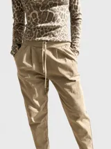 Pantalón tipo babucha de corte holgado, color negro, con cintura elastizada y cordón ajustable. Presenta pinzas delanteras, bolsillos laterales y terminación con dobladillo en los tobillos.