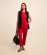 Pantalón de crepé rojo, modelo estilo pijama, de corte fluido, con cintura elástica y lazo de ajuste con terminales metálicas. Cuenta con bolsillos laterales y cierre frontal con cremallera y botón.