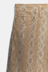 Pantalón de tiro medio en color marrón con diseño de animal print y aplicaciones de brillos en contraste. Cuenta con cinco bolsillos, presillas para cinturón y cierre frontal con cremallera y botón metálico.