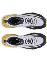 Championes de running Under Armour modelo Halo Racer, con diseño técnico de alto rendimiento. Presentan una parte superior de malla transpirable en color blanco con detalles en azul marino y amarillo. La entresuela destaca por su geometría de balancín con tecnología de amortiguación HOVR+ en tonos amarillo y gris oscuro, diseñada para maximizar el retorno de energía y la estabilidad.