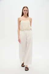 Pantalón de lino blanco, de corte ancho y tiro alto con cintura elástica fruncida y cordón ajustable.