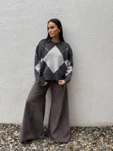 Sweater de punto con diseño de rombos en tonos gris oscuro y gris claro, de corte holgado, cuello redondo y manga larga.