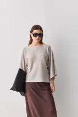 Sweater de punto liviano negro, con escote bote y mangas amplias de largo tres cuartos que aportan una silueta relajada y fluida.