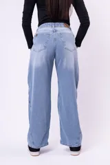 Jean de corte baggy con tiro medio, diseño de pierna ancha y costuras laterales decorativas. Presenta un lavado claro con efecto desgastado.