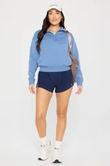 Short deportivo de tiro alto color azul marino, con diseño de corte curvo en los laterales y logo reflectante en la parte inferior. Cuenta con cintura elástica ancha y calza interior incorporada.