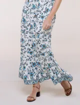 Vestido maxi de rayón con estampado floral en tonos azules y marrones sobre base blanca, con escote en V, mangas cortas y falda larga fluida con volado en el ruedo.