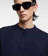 Polo de hombre manga corta en color azul marino, confeccionada en tejido de algodón con textura de malla. Presenta cuello mao con cierre frontal de dos botones.