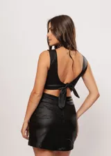 Minivestido negro de gabardina strech metalizada, con escote en V, cut-outs laterales y espalda con lazo ajustable.