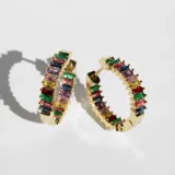 Par de aros tipo argolla dorados, cubiertos de cristales multicolores.