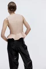 Chaleco de sarga en mezcla de algodón, con escote de pico, botonadura sencilla y diseño con peplum acampanado en la cintura. Prenda forrada.