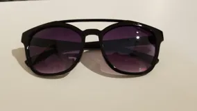 Lentes de sol con montura gruesa de acetato color negro y lentes de color violeta degradado. Diseño con doble puente.