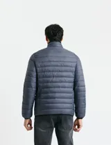 Campera acolchada tipo puffer en color gris, con cierre frontal, cuello alto y puños elásticos.