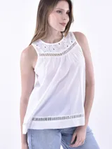 Blusa blanca sin mangas con cuello redondo, confeccionada en tela liviana con detalles de bordado inglés en el canesú y en el ruedo.