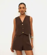 Short sastre de cintura alta, color blanco, con bolsillos laterales y detalles de tachuelas metalizadas.