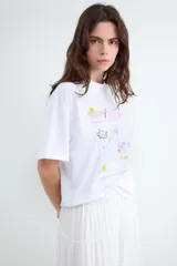 Camiseta blanca de algodón con cuello redondo, manga corta y estampado gráfico delantero en tonos rosados, amarillos y celestes de estilo Y2K.
