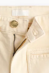 Jean de denim de algodón color beige, de tiro alto y pierna ancha con bolsillos parche delanteros y traseros.