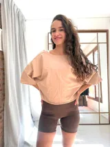 Remera corta de manga corta color celeste, con escote amplio en la espalda que se anuda en la parte inferior, dejando ver un top deportivo amarillo con tiras cruzadas.