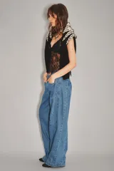 Jean de corte wide leg en color azul medio, con costuras verticales decorativas a lo largo de las piernas y diseño de tiro medio.