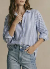 Camisa oversize de algodón con estampado de rayas verticales celestes y blancas, cuello clásico y mangas largas con puños abotonados.