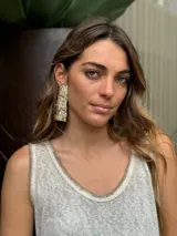 Aros colgantes dorados con textura irregular y detalles de piedras rosadas.