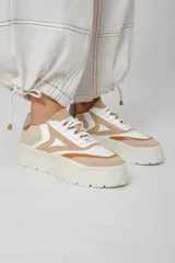 Zapatillas deportivas de cuero color beige, blanco y marrón, con cordones y suela de goma.