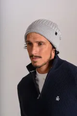 Gorro tipo beanie de tejido acanalado en color gris, con etiqueta pequeña con logo en el lateral.
