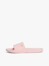 Ojotas tipo slide color rosa pálido, con pala ancha que presenta un patrón de monograma TH en relieve. Cuentan con una pequeña insignia metálica dorada del monograma TH en la tira y el logo de Tommy Hilfiger en relieve en la entresuela.