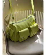 Bandolera color verde lima de tamaño grande, con dos bolsillos frontales y dos bolsillos laterales con broche imán. Tiene correa regulable y extraíble, interior forrado y bolsillo interno con cierre.