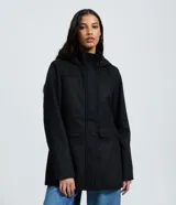 Campera alargada de polivelour color negro, con cuello alto, capucha integrada, mangas largas y bolsillos frontales con solapa. Presenta recortes decorativos en el frente y cierre frontal oculto.
