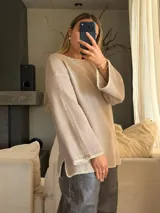 Sweater de tejido de punto jersey en color beige, con silueta oversize, cuello a la base y mangas acampanadas. Presenta terminaciones hechas a mano en crochet a contratono con sutiles detalles de lurex.
