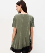 Remera verde militar de algodón con efecto desteñido, cuello redondo, mangas cortas, recortes asimétricos y detalle de encaje negro en el bajo irregular.