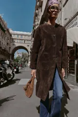 Abrigo de piel color marrón, con cuello redondo, manga larga, cierre frontal con botones y dos bolsillos delanteros de plastrón.