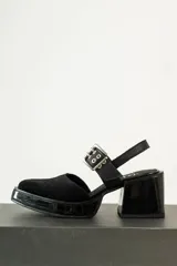 Zapato de tacón cuadrado color negro, con capellada de gamuza y correa al tobillo con hebilla metálica.