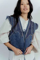 Chaleco de jean azul con bordados y estampado en el interior.